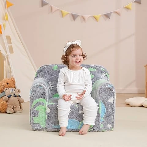 A girl sitting in an armchair, with a teddy bear to the left of the image.